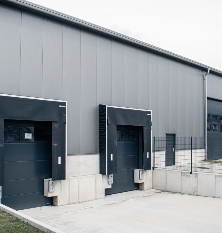 Industriegebäude mit mehreren Laderampen und grauer Fassade.